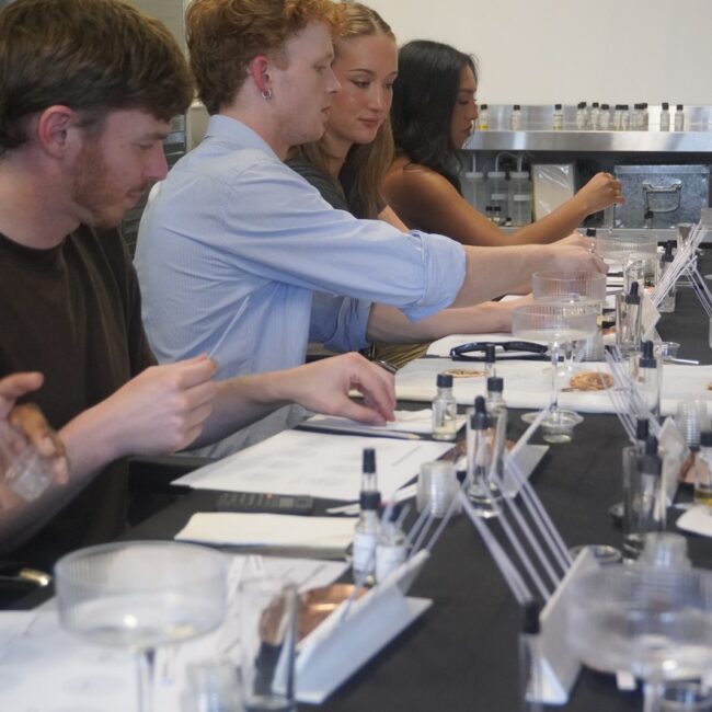 Workshop participants choosing essences at a table of perfumery materials.