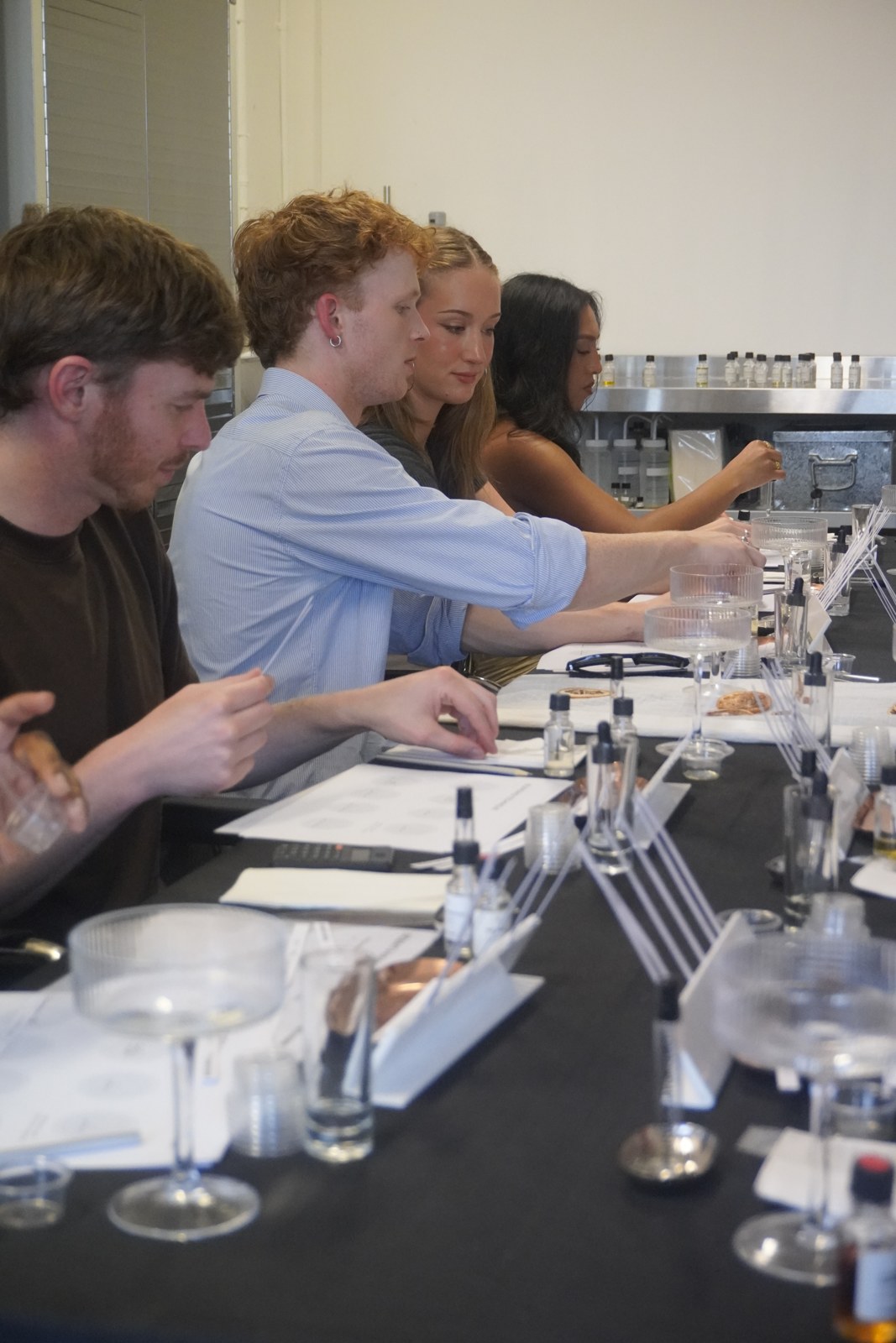 Workshop participants choosing essences at a table of perfumery materials.